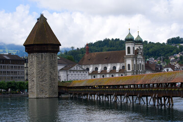 Famous wooden Kappelbrücke (Chapel Bridge) at the old town of Lucerne with medieval stone water...