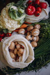 seasonal vegetables in a reusable grocery basket top view. farm vegetables from the local market. young potatoes, champignons, tomatoes, carrots, cauliflower, and greens