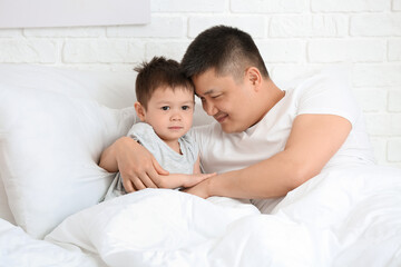 Morning of father and his little son in bedroom