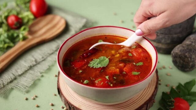 Hand serving tomato rasam curry hot spicy soup South Indian cuisine 4K slow motion footage Indian spices tomato cumin. Traditional vegetarian dish rice onam sadhya Kerala, Tamil Nadu, India Sri Lanka.