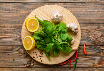 Fresh basil leaves, lemon and spices on wooden background