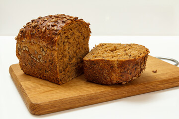 Cut loaf of bread on wooden cutting board on white background