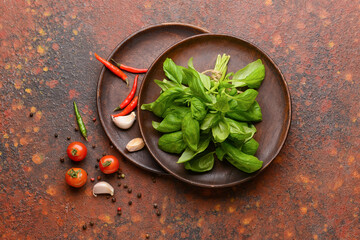 Plates with fresh basil leaves, spices and tomatoes on grunge background
