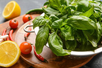 Colander with fresh basil leaves and different products on table, closeup
