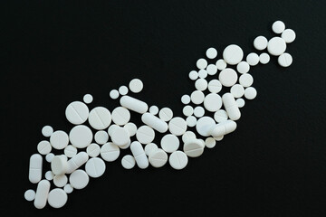 Lots of white pills on a black background.
View from above.