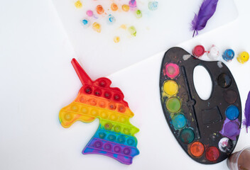 Fototapeta na wymiar Children's toy popit unicorn of rainbow colour from soft plastic. Development of fine motor skills in child. Entertainment for children at home in family.