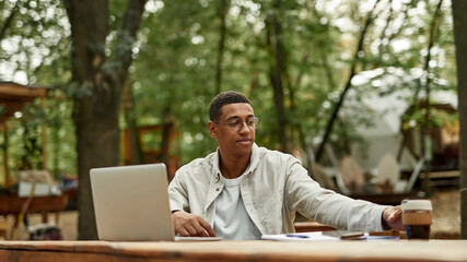 Smiling young african american man working on laptop