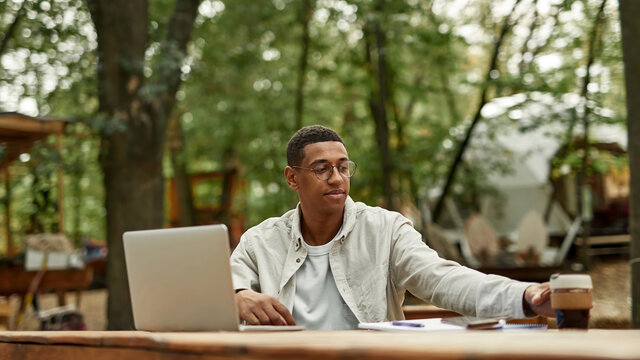 Smiling young african american man working on laptop