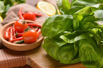 Fresh basil leaves, tomatoes and chili peppers on table, closeup