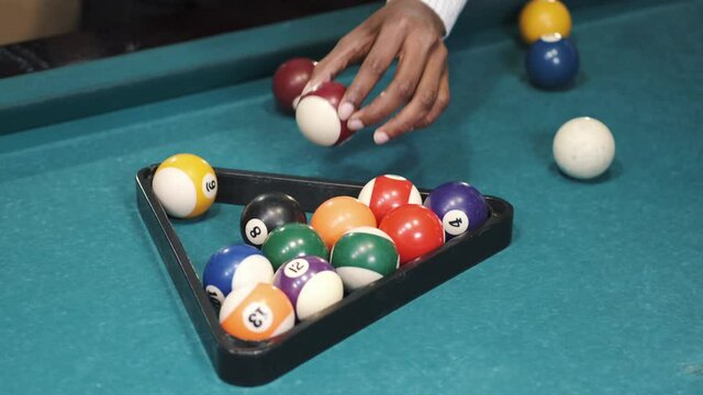 Man puts on the pool table balls in a triangular frame