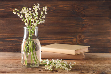 Vase with beautiful lily-of-the-valley flowers on wooden background