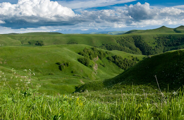 Green hills of the foothills of the Caucasus Mountains, mountain ranges are visible in the distance. Russia.