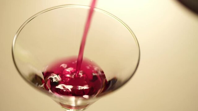 Slow motion._bartender pouring cocktails or juice into a martini glass