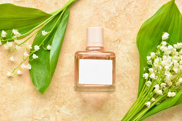 Bottle of perfume and lily-of-the-valley flowers on color background