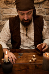 medieval man sitting on a table and playing dice, concept gambling