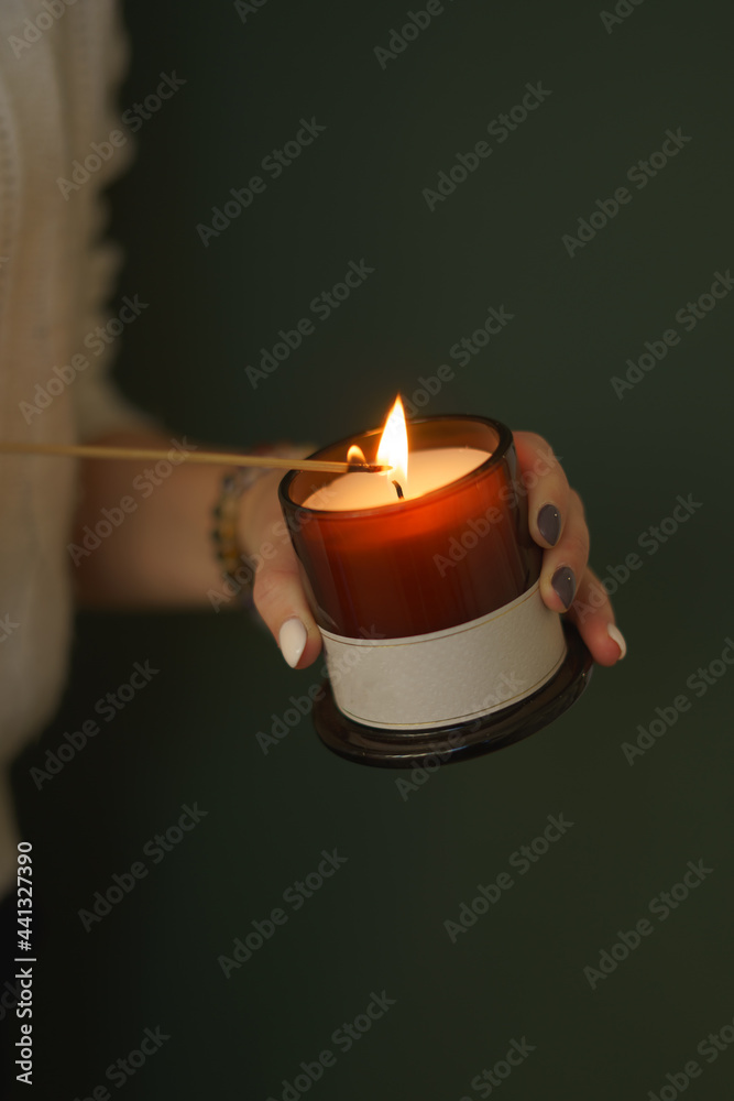 Wall mural on a green background, an orange candle and the girl's hands light a candle with a splinter