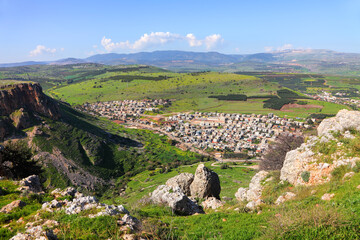 Arbel Cliff flowering beautiful landscape. Arbel National park. Nature reserve. View from the mountain on agriculture valley with green plantations and Arabic modern settlements. Low Galilee, Israel - obrazy, fototapety, plakaty