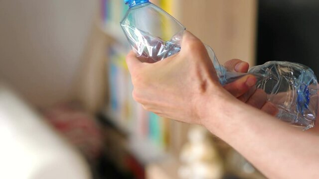 Crushing the plastic bottle with hands in 4k slow motion 60fps
