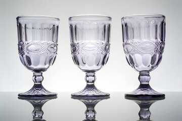 three finely decorated crystal cups on a neutral background, still-life composition