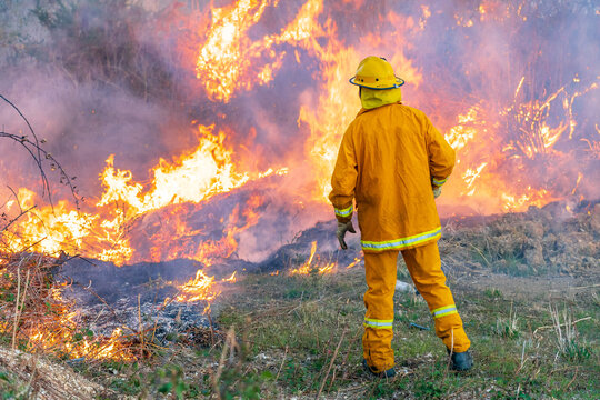 A fireman stands watch over a blazing grass fire