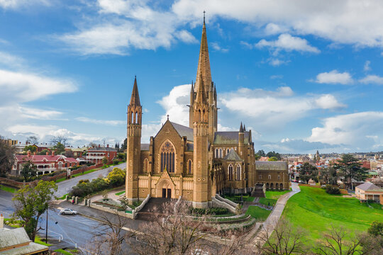 Aerial view of a cathedral on a grassy hillside in a regional city