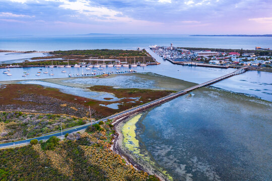 Aerial view of a narrow bridge over a shallow coastal bay at twilight