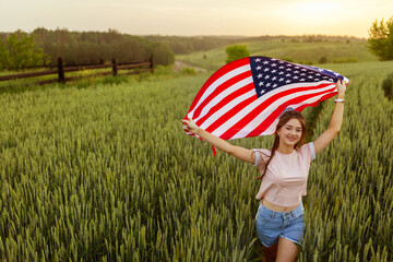 young happy beautiful  girl in pink top and jeans shorts with national American flag  in green...