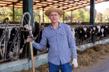 Portrait of a confident male standing on a livestock farm with a pitchfork in his hand