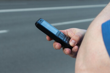 push-button phone in the hands of a man close-up on a gray background