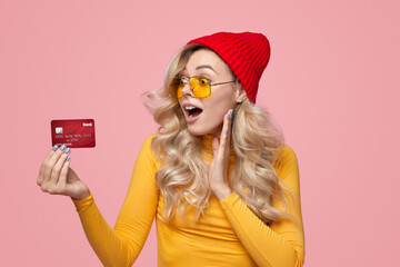 Amazed young woman with bank card