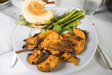 A hamburger with asparagus and roasted sweet potatoes.