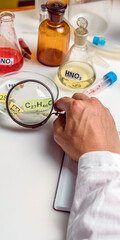 Fototapeta premium Food specialist looking at a plate with the name of a food additive through a magnifying glass, food quality. Vertical format.