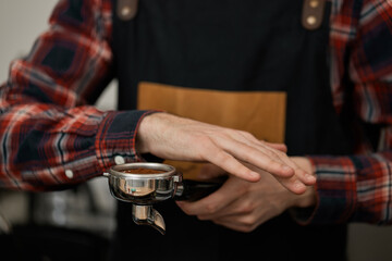 male waiter in apron holding holder for a coffee machine
