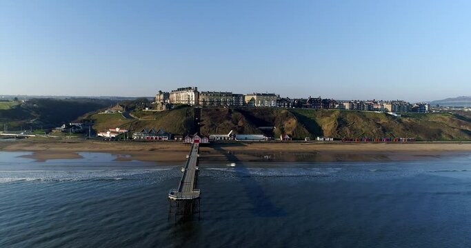 Saltburn By The Sea - Drone out over Pier, slow elevation out from pier, with full view over Saltburn Town and Victorian Seafront, with funicular railway - Summer