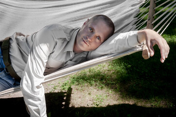 A man in a shirt lies in a hammock in the yard