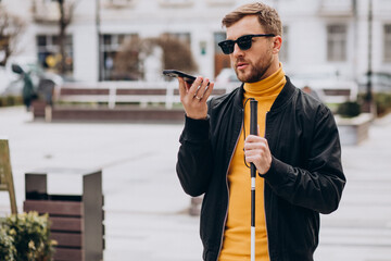 Young blinded man using phone and sending voice message
