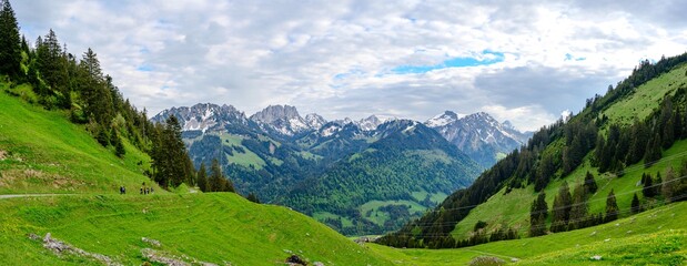 View on alps mountains, cloudy sky, green fields by Jaun, kanton Fribourg, Freiburg nearby Bulle, Bern, Thun. Good hiking tourist way. Switzerland.