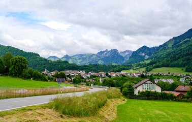Obraz premium View on alps mountain, green fields Bulle, kanton Fribourg, Freiburg nearby Bern. Castle Greyerz Good hiking tourist way. Switzerland.