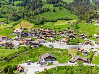 View on alps mountains, green fields, cloudy sky, Church by Jaun,  Jaunpass. Canton Fribourg, Freiburg nearby Bulle, Bern, Thun. Good hiking tourist way. Switzerland.