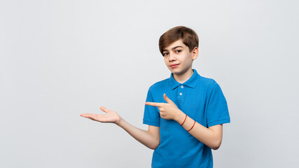 Handsome boy looking at the camera and showing aside on copyspace. Pay attention to important...