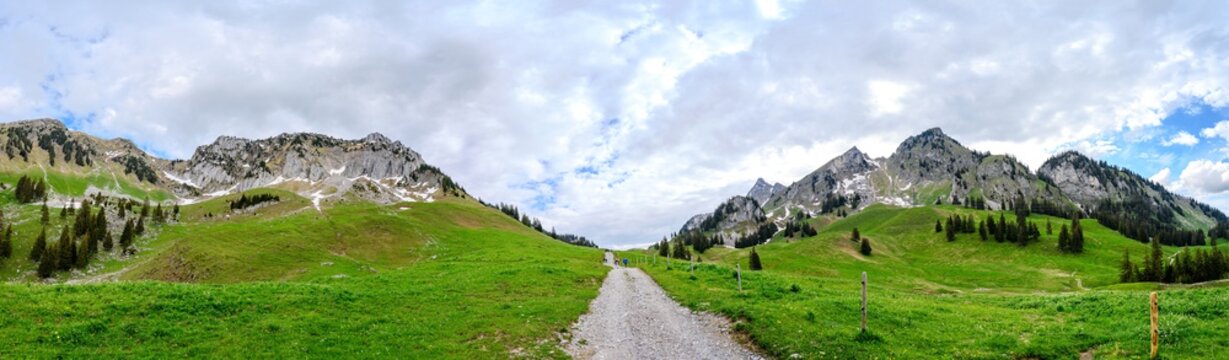 View on alps mountains, cloudy sky, green fields by Jaun,  kanton Fribourg, Freiburg nearby Bulle, Bern, Thun. Good hiking tourist way. Switzerland.
