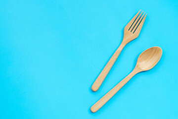 Wooden spoon and fork on blue background.