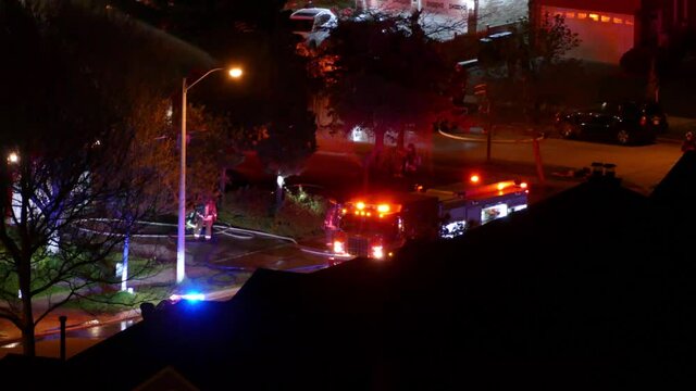 Firefighter and Flashing Blue And Red Sirens From Fire Engine, Residential Neighbourhood, Evening, Long shot