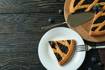 Заголовок: Delicious blueberry pie on rustic wooden background with kitchen towel

