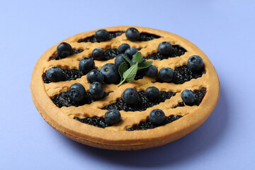 Delicious blueberry pie with berries on violet background