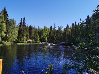 A picturesque waterfall on the Tokhmayoki River in Karelia surrounded by trees on a clear summer...