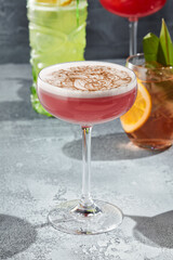 The Clover Club Cocktail is a cocktail consisting of gin, lemon juice, raspberry syrup, and egg white. Red Clover Club Cocktail with white foam and cinnamon powder. Vintage table,  sunshine and shadow