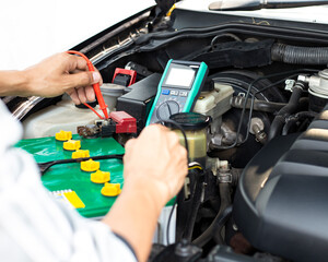 A technician is checking the car battery for availability.;	