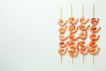 Tasty grilled shrimps skewers on white background