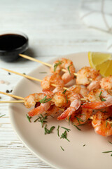 Plate with grilled shrimps on white wooden background